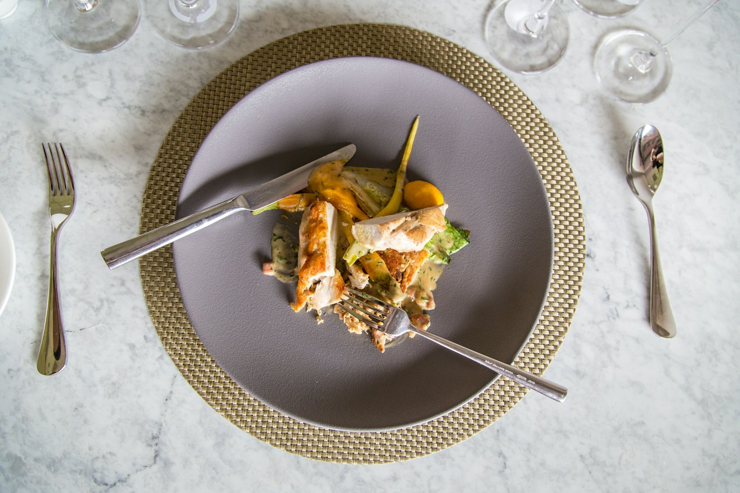 Grilled chicken and vegetables plated on a grey plate on a placemat.