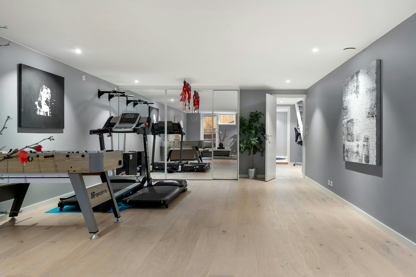 Modern home gym with a foosball table and two treadmills.